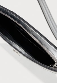 Calvin Kleini õlakott mustast nahast välispinnaga, hõbedaste tõmblukkude sulgemisega ja must sisemus. Omab välispinnal reljeefset logo.