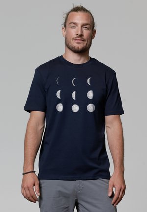 Marineblaue T-Shirt aus weichem Stoff, das eine Grafik der Mondphasen in Weiß zeigt. Mit kurzen Ärmeln und rundem Halsausschnitt.