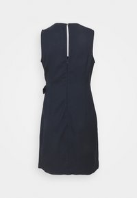 Černé šaty bez rukávů ke kolenům s zipem na zádech a malým zlatým knoflíkem na vrchu, zobrazené na jednobarevném bílém pozadí.