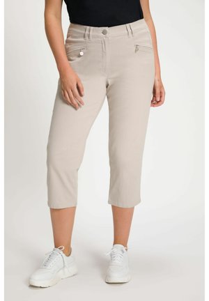Beiga cropped byxor i en texturerad tygkvalitet, med dragkedjefickor, knappstängning och en figurnära passform. Matchade med vita sneakers.