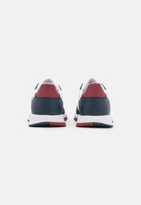 Scarpe sportive bianche con dettagli in blu navy e bordeaux. Presentano un tallone texturizzato, una suola ammortizzata e un design slanciato.
