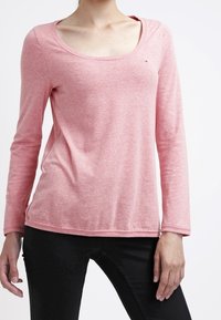 Ljusrosa långärmad skjorta i mjukt tyg med rundad halsringning. Har en diskret logotyp på bröstet och en avslappnad passform.