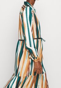 Abito lungo e bottonato caratterizzato da righe verticali in teal, marrone e crema. Realizzato in un tessuto liscio con vita arricciata e maniche con polsini.