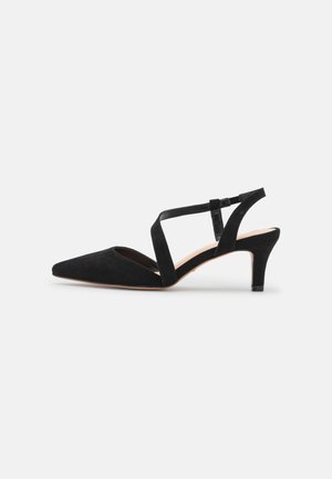 Czarny zamszowy niskokroczący but na obcasie typu slingback z szpiczastym noskiem i skrzyżowanymi paskami na jasnoszarym tle.