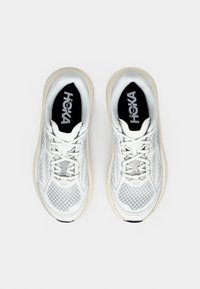 Hvite sportssko med mesh-overdel, snøring og nøytralfarget gummisåle. Har merke på svart innersåle.