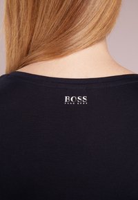 Námořnické tričko s širokým výstřihem, krátkými rukávy a stříbrným logem "BOSS HUGO BOSS" na zadní straně, vyrobené z hladké, jemné tkaniny.