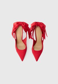 Røde satin høje hæle med spids snude, udstyret med store sløjfer på ankelstropperne og åbne sider for et delikat design.
