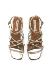Sandali con cinturini in oro metallico con finitura testurizzata. Punta quadrata, cinturini intrecciati e un'intersuola imbottita per comfort e supporto.