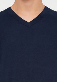 Sweater azul-marinho em forma de V, feito de um tecido de malha suave. Apresenta um decote canelado e uma textura lisa, adequado para uso casual.