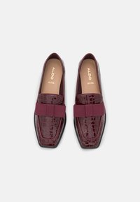 Mocassins bordeaux avec une texture crocodile brillante, dotés d'une large bande élastique sur le devant et d'un design à bout pointu.