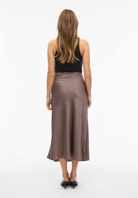 Satin midi nederdel i en mørk taupe farve, glat tekstur, flared kant og høj talje, parret med en sort tanktop og sorte hæle.
