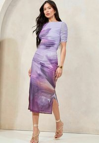 Violet mekko, jossa on kukkakuosi, ryhditetty kangas, lyhyet hihat ja sivuaukko. Pehmeä tekstuuri, keskikokoinen malli, yhdistettynä nauhassa oleviin sandaaleihin.