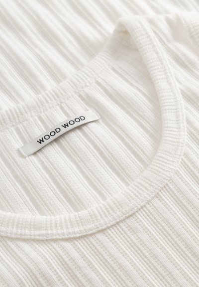 Hvit ribbestrikket singlet med rund halslinning, synlig tekstur og en "WOOD WOOD" merkeetikett sydd i halslinningen.