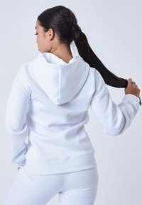Witte hoodie met geribbelde manchetten en zoom, met een relaxte pasvorm en zachte katoenmix textuur, gezien vanaf de achterkant met een lange paardenstaart.