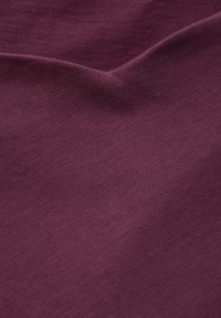 Burgunderfarbener Stoff mit einer glatten Textur, der leicht dehnbar ist und einen subtilen Glanz aufweist. Das Material wirkt leicht und weich.