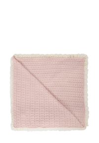 Różowy koc waffle o teksturowanej powierzchni z falbaną z białej koronki, złożony, aby odsłonić obie strony. Lekki i miękki.