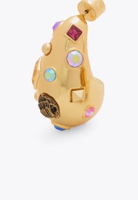 Ciondolo color oro con vari rhinestone colorati e forme geometriche. Dettagli notevoli includono un design a mano testurizzato e una base blu.