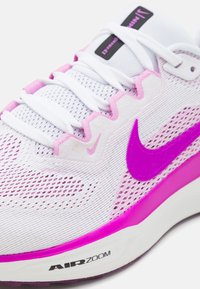 Bijele mrežaste tenisice za trčanje s ružičastim detaljima, s istaknutim ljubičastim Nike logotipom, teksturiranom površinom i jastučićem Air Zoom.