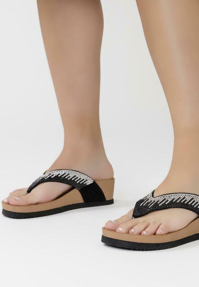 Chanclas de cuña en negro y beige con una parte superior texturizada y acentos plateados, plantilla acolchada y suela de goma.