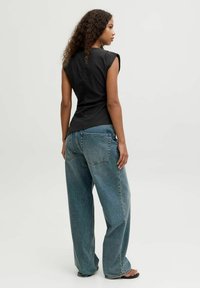 Sort tætsiddende top med korte, strukturerede ærmer, parret med løse, højtaljede jeans i medium vask. Glat stofstruktur, afslappet design.