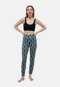 Leggings moulants bleu foncé, ornés d'un motif géométrique ondulé en vert clair et ivoire, fabriqués en tissu extensible.