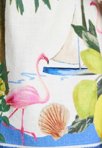 Fabric featuring a pink flamingo, seashell, sailboat, and lemons against a white background with colorful tropical foliage and blue accents.