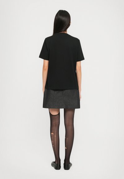 Μαύρο μπλουζάκι, κοντά μανίκια, σε συνδυασμό με γκρι τζιν φούστα. Οι καλτσόν έχουν σκισίματα και σχέδια; μαύρα φλατ ολοκληρώνουν την εμφάνιση.