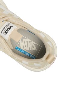 Zapatilla Vans beige con parte superior de tela texturizada, rayas blancas y plantilla Ultracush gris que presenta detalles de marca en azul y blanco.