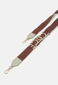Cinghia in tessuto marrone con un accento in pelle verde chiaro e hardware dorato, caratterizzata da un motivo con logo ripetuto e lunghezza regolabile.