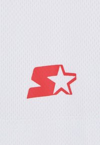 Tela blanca con una textura de malla que presenta un destacado logo rojo en forma de "S" con una estrella. Diseño simple, sin patrones ni acentos adicionales.