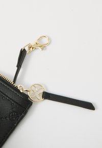 Black leather wallet with a textured surface, gold hardware, lobster clasp, and a decorative circular accent attached. Zipper closure detail visible.