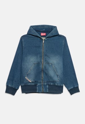 Sweat à capuche bleu style denim avec fermeture éclair devant, poche kangourou, poignets et ourlet côtelés, et une étiquette rouge de la marque Diesel à l'intérieur du col.