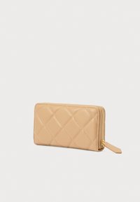 Brązowy pikowany portfel wykonany z gładkiej skóry, wyposażony w zamek błyskawiczny i małą metkę. Prostokątny kształt z akcentami w formie diamentowego wzoru.