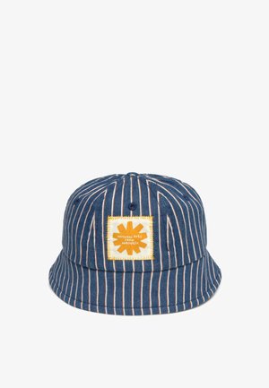 Chapeau bob à rayures verticales bleues et blanches avec un patch carré jaune portant l'inscription "Colorants naturels d'Auroville" à l'avant.