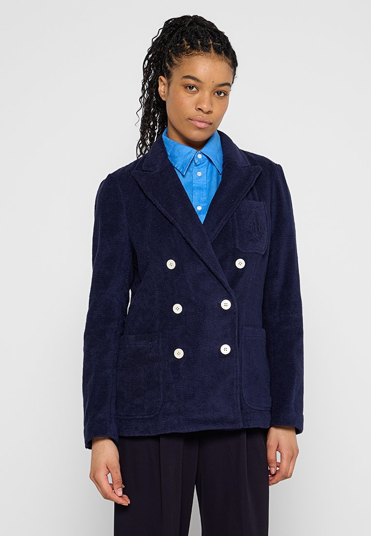 Granatowa podwójnie zapięta marynarka z miękkiego materiału, z dwiema dużymi kieszeniami z przodu i kremowymi guzikami, z dopasowanym kołnierzem i teksturowanym wykończeniem.