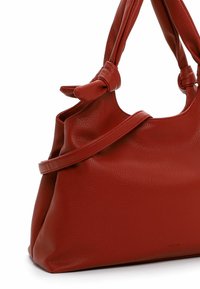 Bolso de mano de cuero rojo con un acabado texturizado, que presenta un asa anudada y una forma estructurada. Diseño minimalista sin herrajes visibles.