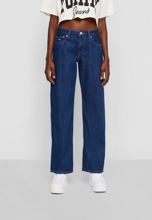 Dark blue denim wide-leg jeans with front pockets, a button and zip closure, and contrast stitching, paired with white sneakers.