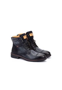 Botas de tobillo de cuero negro y ante con punta redonda, cierre de cordones en la parte frontal y forro marrón. Incluye una etiqueta con el logo y un detalle de costura en contraste.