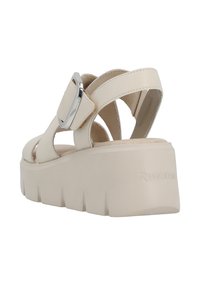 Sandales à plateforme beiges avec une large bride, une boucle argentée et une semelle texturée. Le matériau semble synthétique, offrant un design décontracté.