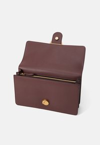 Burgundy leather bag with a structured design. Features a gold zipper, a button closure, and an interior pocket. Smooth texture.