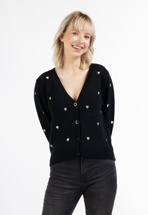 Zwarte cardigan met een diepe V-hals en een gouden hartpatroon. Heeft knopen aan de voorkant en ribgebreide manchetten en zoom. Lichtgewicht gebreide structuur.