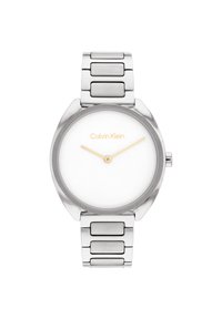 Reloj de metal plateado con caja redonda, esfera blanca, marcadores y agujas doradas, y una pulsera de eslabones texturizada y elegante. Logo de Calvin Klein exhibido.