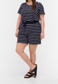 Modrý a bílý pruhovaný dvoudílný set, který zahrnuje tričko s krátkým rukávem a šortky na stažení, vyrobený z měkkého materiálu. Doplněno černými sandály.