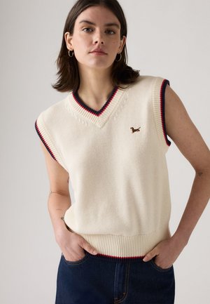 Maglione senza maniche color crema con scollatura a V, rifiniture a coste blu navy e rosse, caratterizzato da un piccolo bassotto ricamato sul petto, lavorazione a maglia testurizzata.
