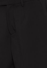 Pantalon noir ajusté avec plis avant, passants de ceinture et fermeture dissimulée.