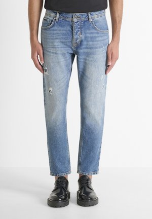 Jeans de denim azul claro con un corte recto, que presentan detalles desgastados, cinco bolsillos y costuras en contraste. Acabados con un cierre clásico de botón.