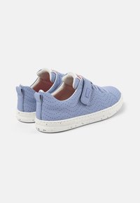 Ljusblå sneakers med perforerat mönster, vit gummisula och justerbar rem. Funktioner inkluderar en vadderad krage och rosa foder inuti.