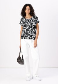Svarte og hvite zebra-stripede kortermede topper kombinert med hvite vide bukser og hvite joggesko, med en avslappet passform og rund hals.