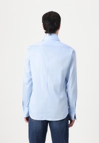 Cămașă albastru deschis cu mâneci lungi, cu guler clasic, spate cu yoke și manșete cu un singur nasture, fabricată dintr-un material de bumbac neted.