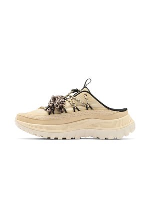 Beiger Slip-On-Sneaker mit dicker, gerippter Sohle, schwarzem Besatz, Leopardenmuster und Kordelschnürsenkeln, die sich über die Vorderseite erstrecken.